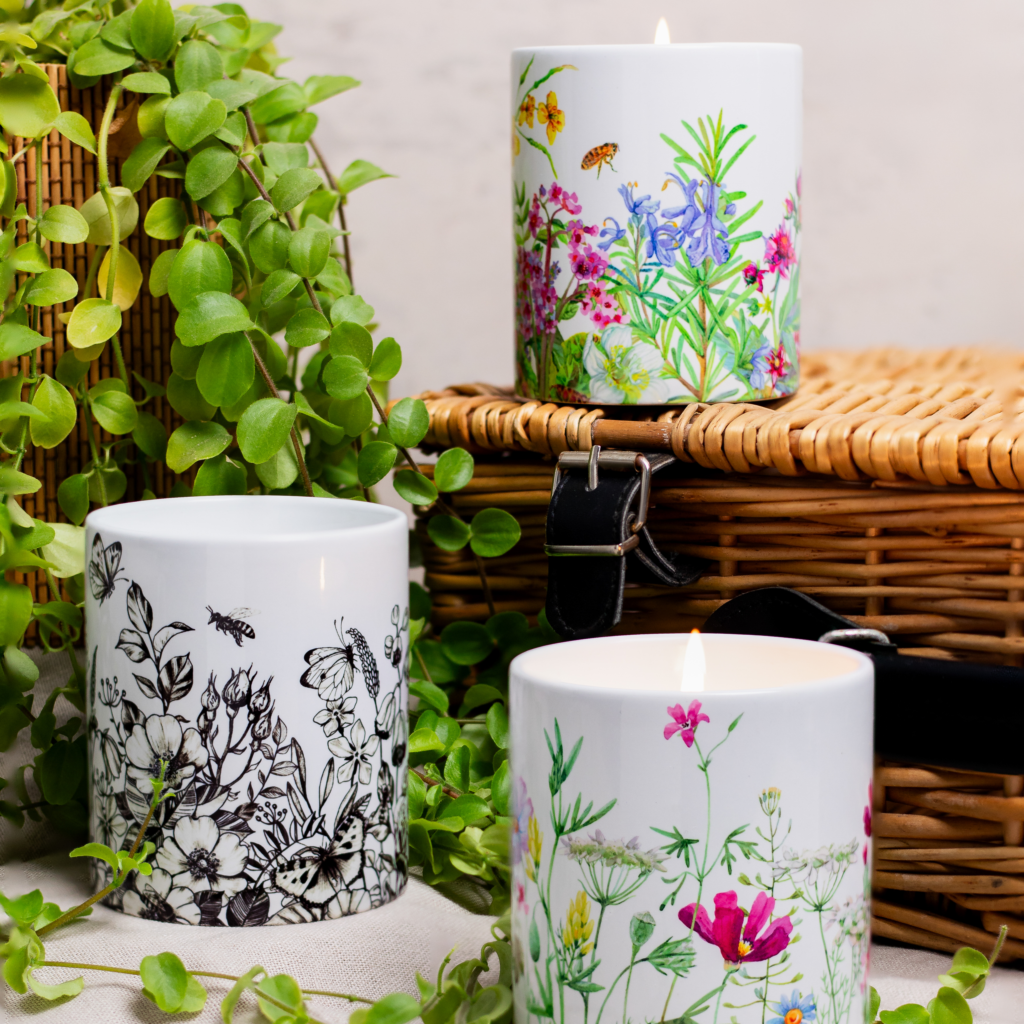 Two Spring Designed Candles. Featuring wild colorful flowers, greenery, bees and butterflies on the ceramic vessel.